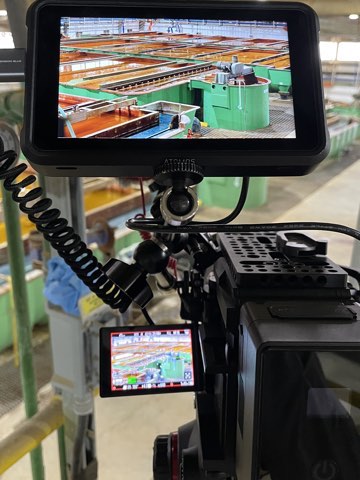 Atomos monitor and Neewer light rigged over an industrial plant floor